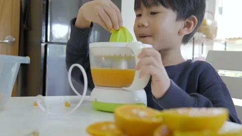 Asian boy making fresh orange juice. Video stock 165681580