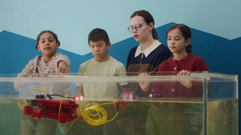 Asian Boy Operating Underwater Robot in Class with Teacher and Diverse Girls Stock Footage 304155734