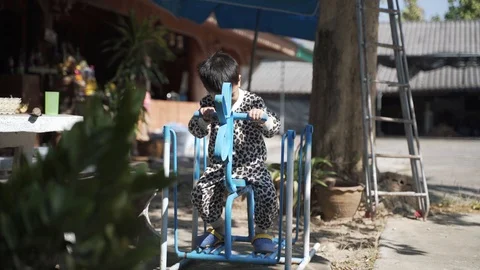 Asian boy playing and having fun with steel swing horse Stock Footage 121516638
