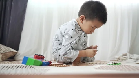Asian boy playing with brick block toy and Thai baht coin money on the bed Stock Footage 119694559