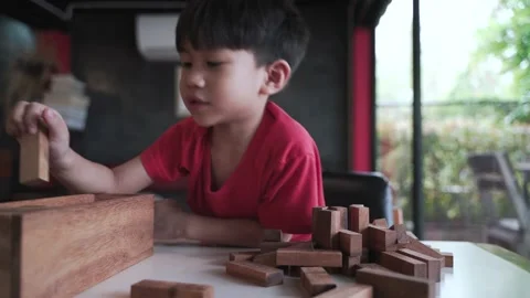 Asian boy playing building block tower by wooden brick Video stock 174019942
