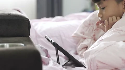 Asian boy playing computer tablet on the bed Video stock 163286959