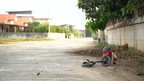 Asian boy playing dirt while exercise with balance bike while his mother running Stock Footage 131132534