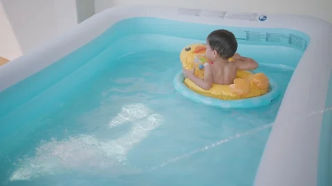 Asian boy playing with duck balloon in portable swimming water pool Video stock 88826217