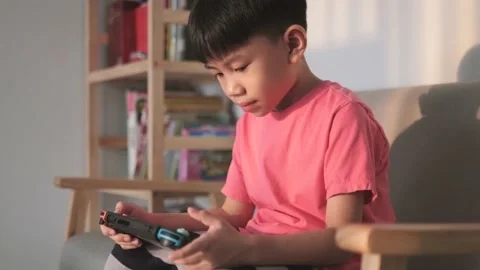 Asian boy playing a portable video game on the couch. Stock-Footage 197365601