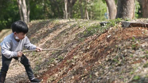 Asian boy playing with steep soil slopes at a public park in Thailand Stock Footage 196663269