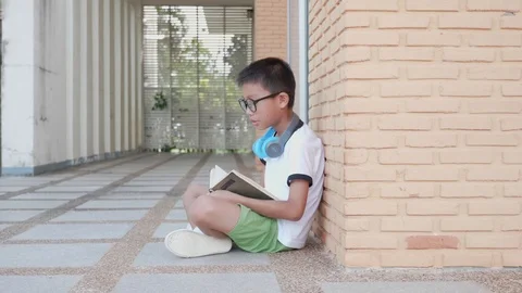 Asian boy reading a book while sitting in the park. Stock Footage 119693570