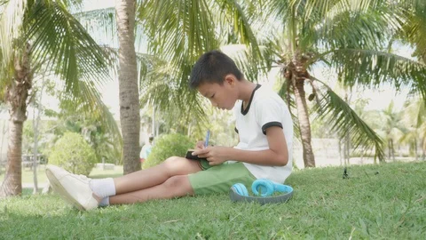 Asian boy reading a book while sitting in the park. Stock Footage 119694385