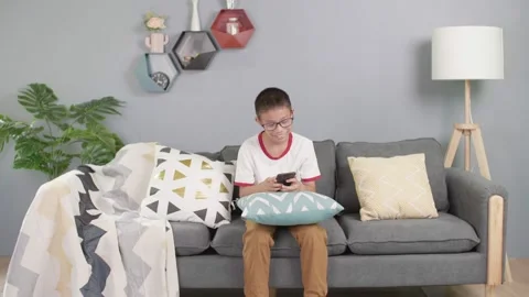 Asian boy sit on sofa and use mobile phone Stock-Footage 157106492