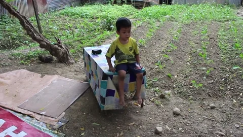 An Asian boy is sitting on a table in the garden Video stock 201319686