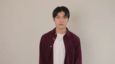 Asian boy smiles at the camera. Dolly in. White wall. Slow-mo. Stock Footage 220783690