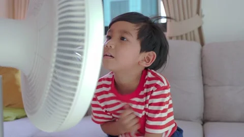 Asian Boy Standing in Front of Fan at Summer. Child Enjoying Cool Wind From Stock Footage 167929672