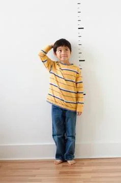 Asian boy standing next to height markers on wall Stock Photos