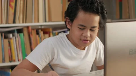 Asian boy student learning studying online with laptop computer in library Video stock 141964620