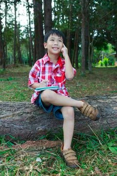 Asian boy thinking to solve a problem on wooden log in park. Education Stock Photos