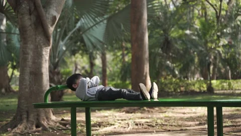 Asian boy trying to do sit up exercise on a bench Stock Footage 148648452
