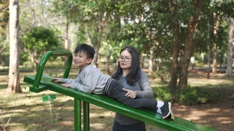 Asian boy trying to do sit up exercise with his mother help Video stock 148648456