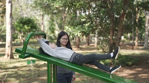 Asian boy trying to do sit up exercise with his mother help Stock Footage 170225159
