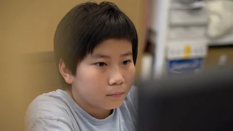 Asian Boy using a computer desktop playing 4K Stock Footage 139566001