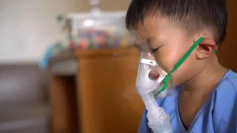 Asian boy using inhaler containing medicine to stop coughing Stock Footage 95185058