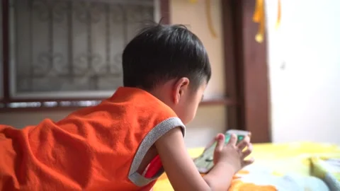 Asian boy using mobile phone play game lying Stock Footage 133646611