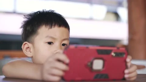 Asian boy using mobile phone for watching cartoon application Stock Footage 141911529
