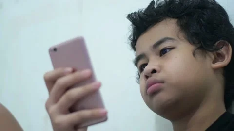 Asian boy using smart phone with bored gesture, learning at home online Stock Footage 140228479