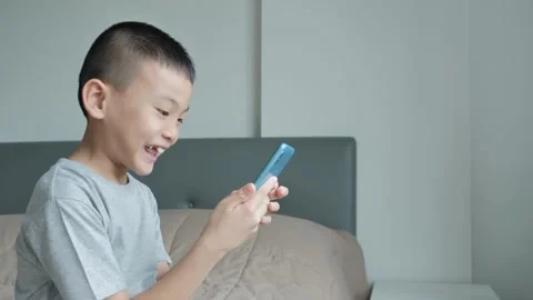 An Asian boy is using a smartphone in the bedroom. Stock Footage 141126462