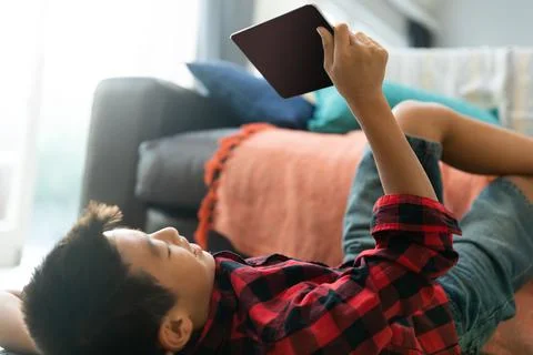 Asian boy using tablet with blank screen lying on floor at home Stock Photos
