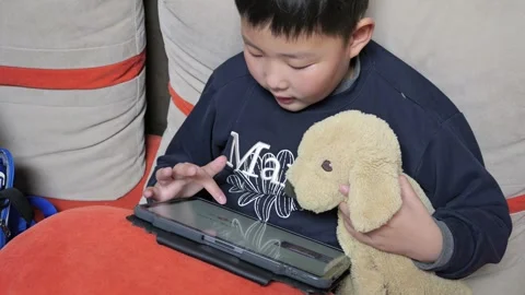 An Asian boy is using a tablet to study English 스톡 동영상 266429213