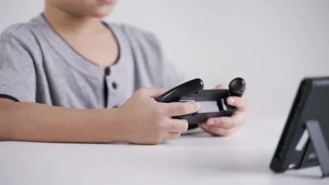 Asian boy using wheel controller for playing the racing video game Stock-Footage 147336722