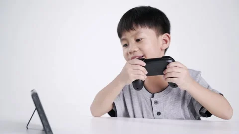 Asian boy using a wireless controller for playing a video game Video stock 147337475