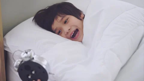Asian boy waking up with shocking expression after looking at late alarm clock o Stock Footage 148698781