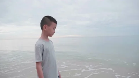 An Asian boy is walking on the beach in the sky on a cloudy morning. Stock Footage 141126416
