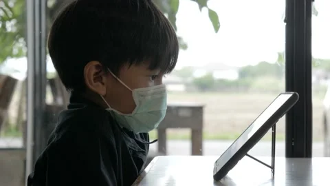 Asian boy watching computer tablet with a medical face mask. Vídeos de archivo 153825334