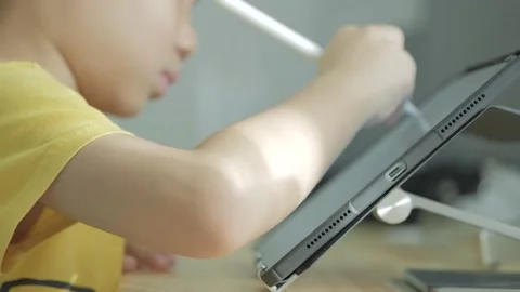 Asian boy writing a letter on a computer tablet with the electric pen. Stock Footage 220244736