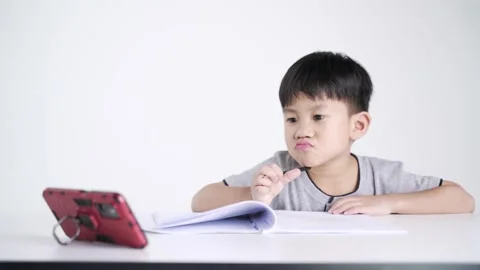 Asian boy writing while watching a mobile phone as studying online Stock-Footage 147337442