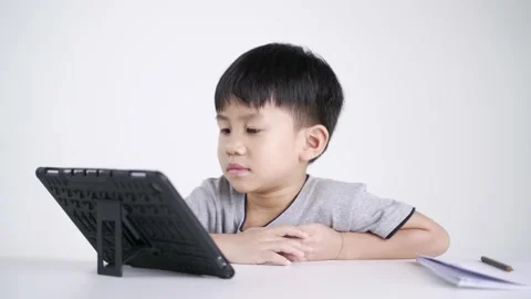 Asian boy writing while watching a mobile phone as studying online Stock Footage 151255974