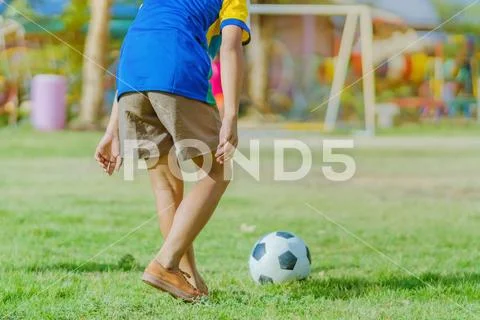 Asian boys practice kicking the ball to score goals in the public football fi Stock Photos