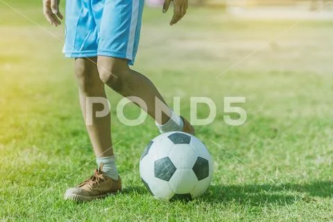 Asian boys practice kicking the ball to score goals in the public football fi Stock Photos