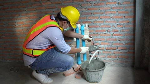 Asian bricklayer worker installing brick masonry Closing pvc pipe for water p Stock Footage 146445618