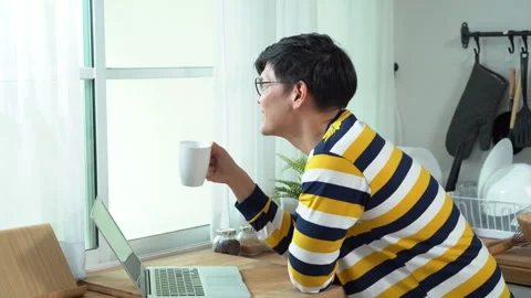 Asian business man using laptop and drinking coffee looking out of window i.. Stock Footage 252820740
