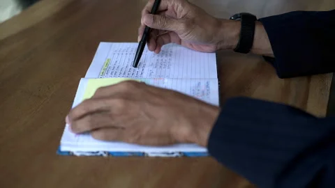 Asian business man writing note a book on wooden table, close up filmed on Stock Footage 336035006
