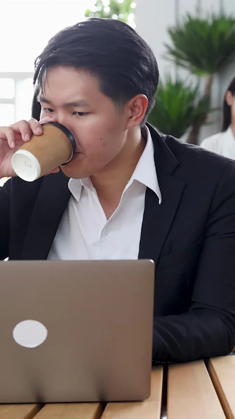 Asian Businessman Drinking Coffee While Working on Laptop in Office Stock Footage 346664788