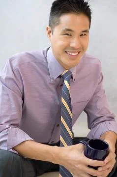 Asian businessman holding coffee mug Stock Photos