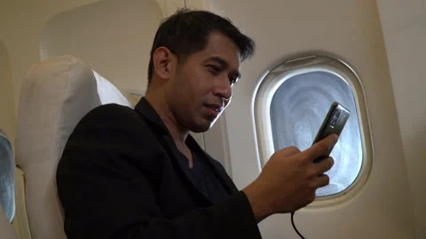 Asian businessman passengers using smartphone sitting in airplane Stock Footage 147239397