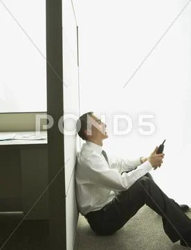 Asian businessman sitting against cubicle wall with telephone Stock Photos