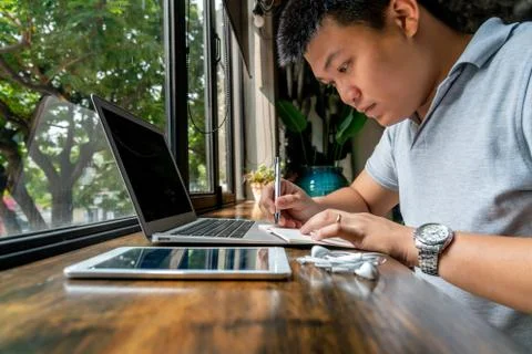 Asian businessman taking notes in front of laptop and tablet Foto stock