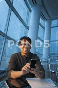 Asian Businessman Text Messaging On Cell Phone