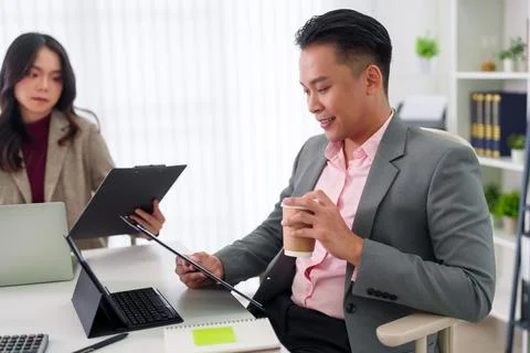 Asian businessman using digital tablet holding coffee cup working at modern.. Stock Photos